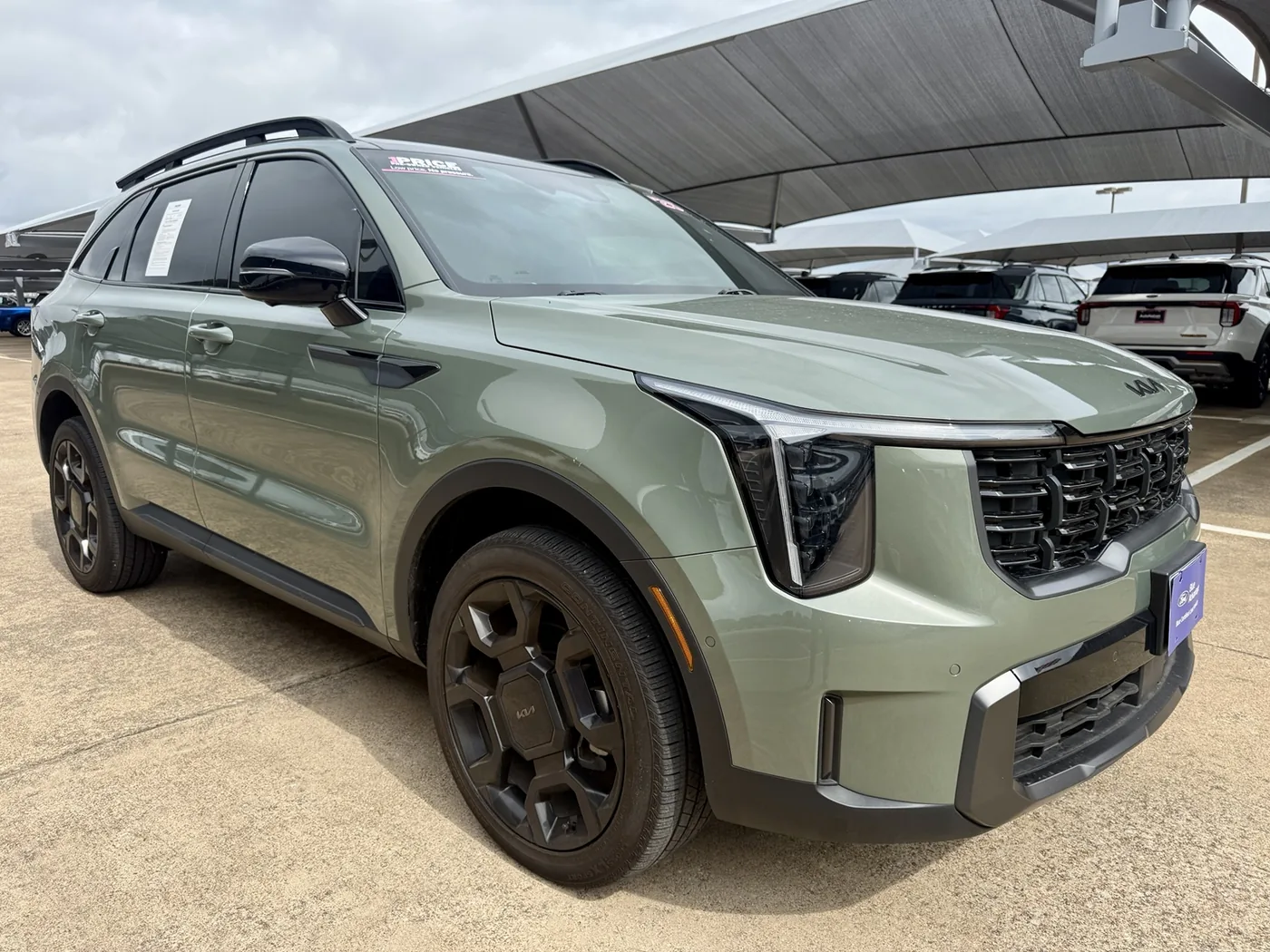 Green Kia SUV photographed at a dealership